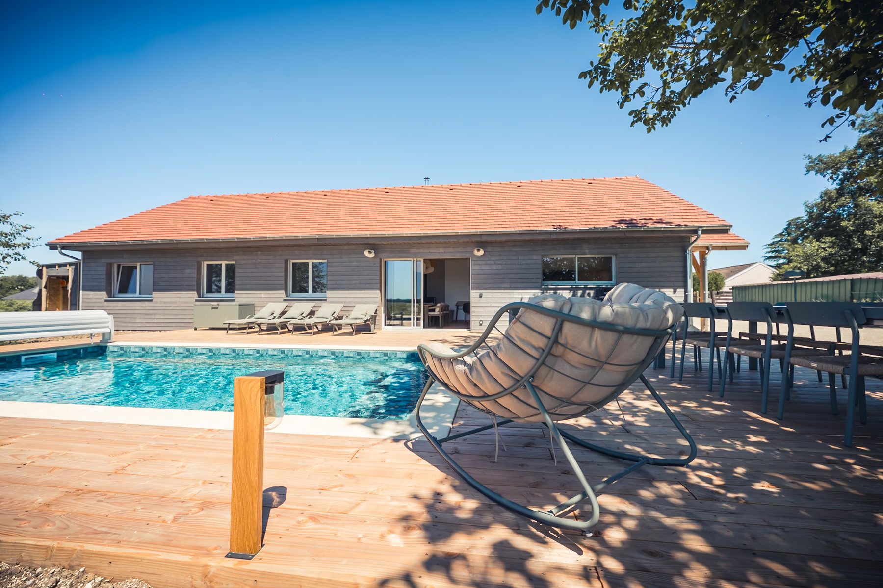 Piscine privée avec terrasse, transats et maison en bois